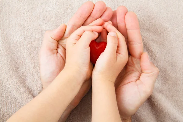 Hände von Erwachsenen und Kindern mit rotem Herz — Stockfoto