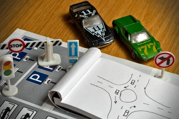 Not defteri, trafik kuralları kitabı, oyuncak arabalar, trafik ışıkları ve masa üzerindeki dur tabelası. Ehliyet sınavına çalışmak ve hazırlanmak