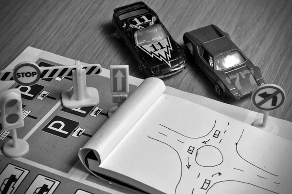 Not defteri, trafik kuralları kitabı, oyuncak arabalar, trafik ışıkları ve masa üzerindeki dur tabelası. Ehliyet sınavına çalışmak ve hazırlanmak