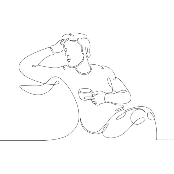 man drinking coffee while sitting on the cushions of the sofa