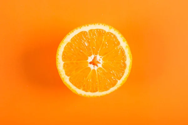 Top view of a half orange fruit on an orange colored background