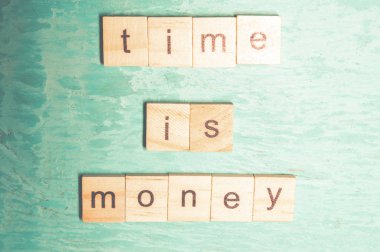 Mavi bir arka plan üzerinde alfabe kavramının ahşap harfleri ile ortaya konulan para kelime zamanı