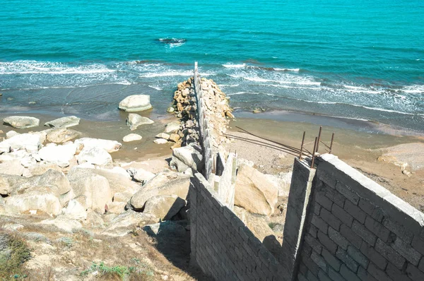Border wall of stones with a lattice on the seashore