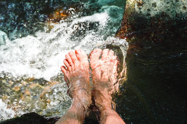 Homens pés em um córrego de água entre o rio Imagem De Stock