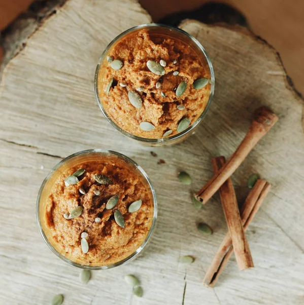 Two portions of pumpkin vegan desserts with cinnamon and seeds. Flat lay view