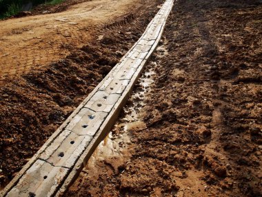 Kapaklarla kaplanmış drenaj oluşturun. Yolun kenarına ıslak zemin üzerine inşa ediliyor. Seçici odak