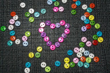 Renkli parlak düğmeler, gökkuşağı renginde düzenlenmiş. Gri arkaplan