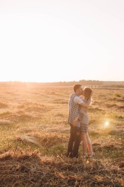 Genç bir çift bir Sunny doğada ayakta akşam ve tutkuyla öpüşme, metniniz için bir yer ile yan görünümü üzerinde