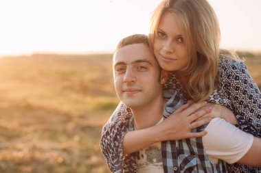 Güneşli havalarda doğada kucaklayan genç ve sevgi dolu bir çift kız adam arkasında tırmandı. Senin metin için yer ile önden görünüm