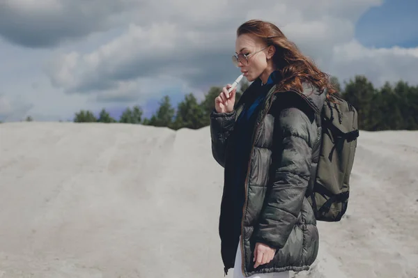 Bir dağ alan üzerinde duran ve elektronik sigara sigara güzel kız.