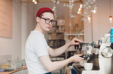 Genç bir adam o kahve makinesi duruyor ve kahve yapar bir Barista çalışır