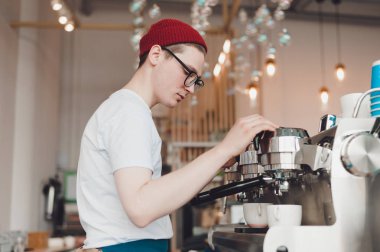Genç bir adam o kahve makinesi duruyor ve kahve yapar bir Barista çalışır