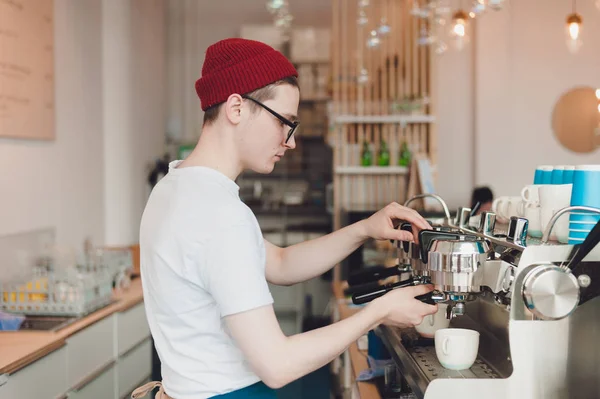 Genç bir adam o kahve makinesi duruyor ve kahve yapar bir Barista çalışır