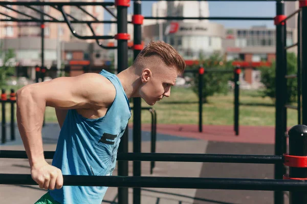 Ein Junger Mann Auf Dem Spielplatz Macht Übungen Barren lizenzfreie Stockbilder