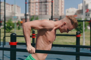 Genç bir adam bir sokak oyun üzerinde spor çubuklarında meşgul