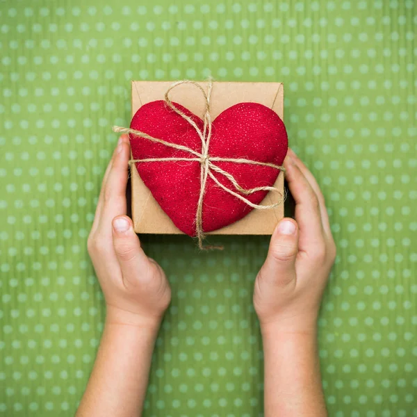 Un bambino tiene un cuore rosso con una confezione regalo — Foto Stock