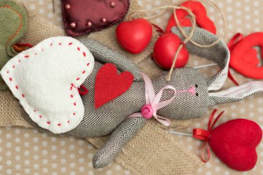 Sevgililer günü. Tavşan karton arka planda beyaz bezelye yatan kırmızı ve beyaz yürekleri el yapımı. Sevgililer günü. Kalp Kolye. Metin için yer. Kırmızı kalpler. Sekizinci Mart.