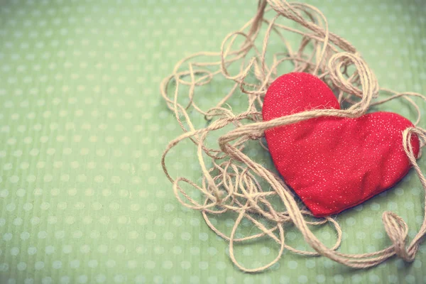 Coeur rouge enveloppé dans du fil vintage sur fond vert — Photo