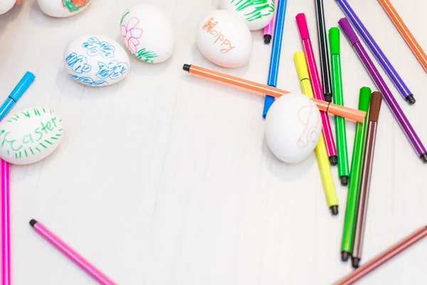 Huevos de Pascua están en la mesa con plumas de fieltro de colores . —  Fotos de Stock