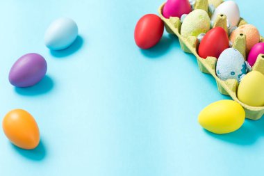 Paskalya yumurtaları parlak renklerde boyanmış, bir karton Eko-ambalaj yalan. Mavi arka plan. Paskalya fikirler. Metin için yer. Yumurta Eko tepsi. Mutlu Paskalya.