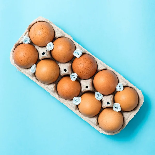 Brown Easter eggs in an eco carton pack lie on a beautiful blue background. Easter ideas. Space for text. Happy easter.