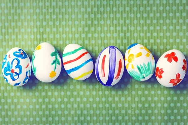 Huevos de Pascua pintados sobre un fondo verde con lunares blancos — Foto de Stock