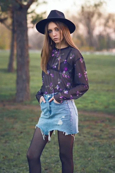Mooi meisje in een denim rok en een transparante blouse. — Stockfoto