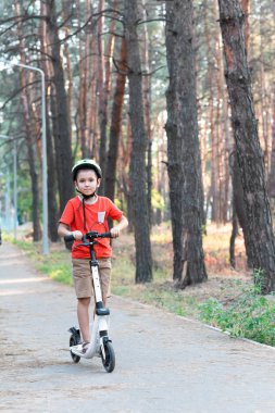 Bir çocuk ormanda scooter kullanıyor..