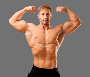 Genç yakışıklı vücut geliştirmeci adam kas görünümü ile poz