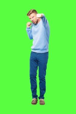 öfkeyle ve kati gösteren bir öfkeli, agresif ve tehditkar poz, dövüş için hazır olan genç sarışın adam yumruk.