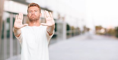 Genç sarışın adam sinyal durağı ile ileri, ciddi ve sert bir ifade ile karşı karşıya avucunun yasaklayan.