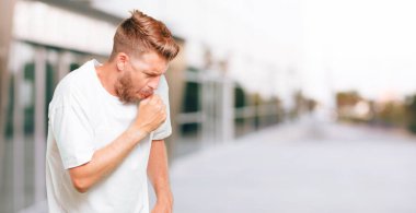 Genç sarışın adam duygu hasta ve ateşli bir kış hastalık soğuk algınlığı veya grip gibi acı Coughing.