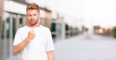 Genç sarışın adam şaka, komik, aptalca ve oynak bir ifadeyle dil yapışkanlık dışarı, bir aptal gibi arıyorsunuz.