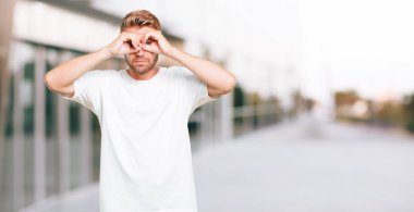 gözler her iki el ile bakmak kapsayan genç sarışın adam korkmuş, korkmuş bir ifade ile.