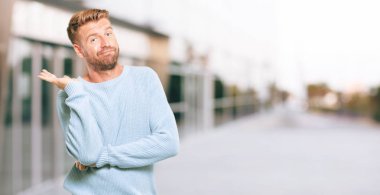 farklı seçenekler veya olanakları merak bir ifade ile arasında şüphe, karşılaştırma ve bir soru poz genç sarışın adam tuhaf ve şaşkın bir bakışla.