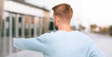 Genç sarışın adam geri görüntülemek, kalça ve sanki karışık ya da düşünceli diğer el ile kafa çizilmemesi yandan.