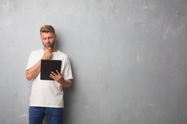 sarışın yakışıklı bir grunge duvardan bir tablet pad için arıyorsunuz