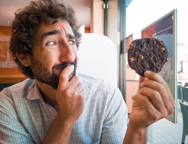 Genç adam bir kahve dükkanında çikolata çerez holding