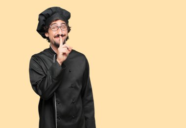 sessizlik isteyen ya da bir sırrı tutmak, ağız, önünde işaret parmağı ile gülümseyen bir şef olarak genç deli adam