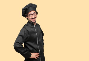 her ikisi ile gurur, memnun ve mutlu bir görünüm ile şef olarak genç deli adam sanki güvenle bakan bir meydan okuma kalçalarına, eller. Akimbo silah geniş bir gülümseme ile poz. Yan veya yan görünüm.