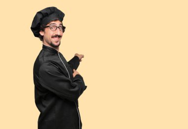 gülümseyen ve yukarı doğru nerede gazeteci bir kavram gösterebilir miyim yere doğru iki eliyle işaret eden bir şef olarak genç deli adam.