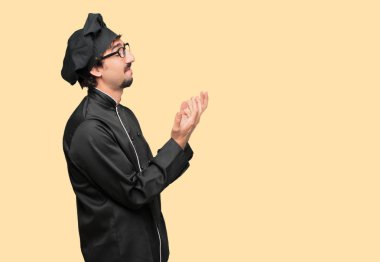 Genç deli adam stresli ve sinirli, yukarı doğru arıyor ve her iki el ele tutuşarak arıyorsunuz bir şef olarak açmak önünde dehşet ve güvensizlik ifade.