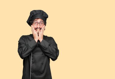 mutlu bir sürpriz ifade ile şef olarak genç deli adam, gözleri geniş açık ve geniş gülümseme, iki eliyle tutarak yüz.