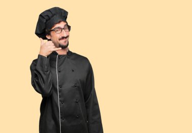 bir telefon görüşmesi jest veya işareti, gurur, mutlu, memnun bir bakışla yapma şef olarak genç deli adam; bir gülümseme ile iletişim sunan.