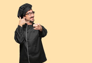 bir telefon görüşmesi jest veya işareti, gurur, mutlu, memnun bir bakışla yapma şef olarak genç deli adam; ileri doğru işaret eden bir gülümseme ile iletişim sunan.