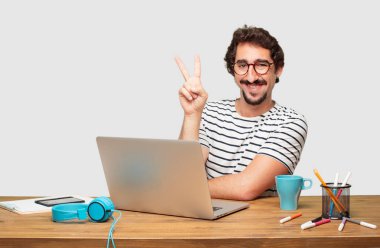 genç grafik tasarımcı ile bir laptop gülümseyen ve görünümlü memnun ve mutlu, iki parmak ile sayılması sakallı.