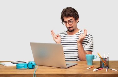 çapraz parmak umutlu, istekli ve heyecanlı bir ifade ile şans için isteyen bir dizüstü bilgisayar ile grafik tasarımcı Genç sakallı.