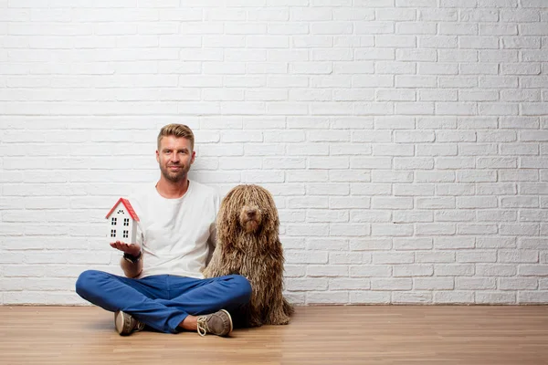 handsome blonde man with a dog and a house model