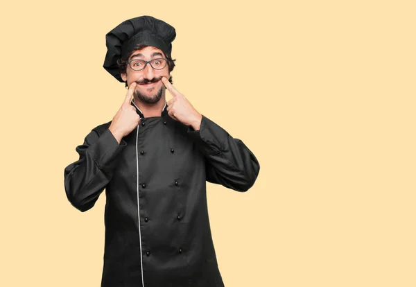 Joven Loco Como Chef Forzando Una Sonrisa Cara Con Ambos — Foto de Stock