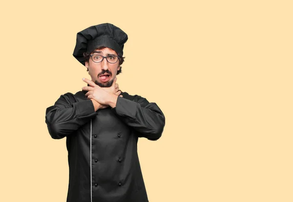 young crazy man as a chef screaming, looking surprised, stressed and terrified, with a gesture of choking with both hands